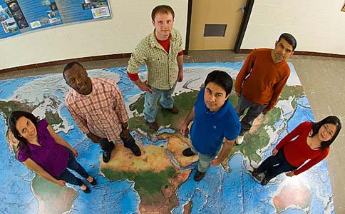 Students standing on world map.