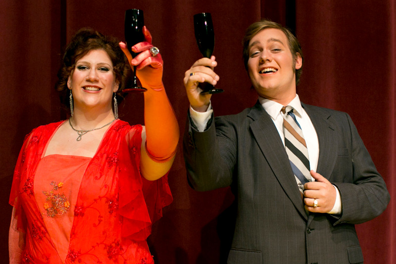 A male and female actor raising a glass of wine