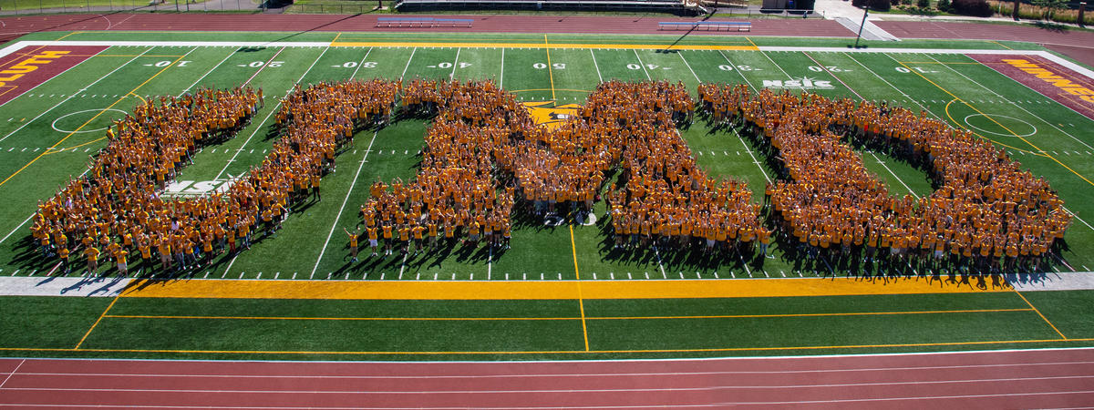 A large group of students on a football field forming the shape of the letters "UMD."