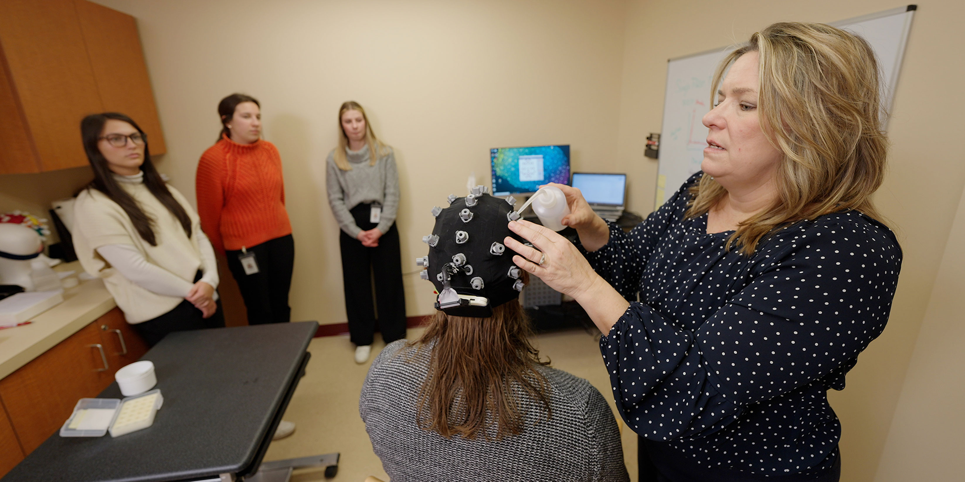 An instructor demonstrates the setup of an Electroencephalogram (EEG) system to a group of students