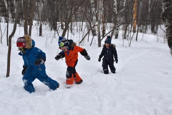 Three children walking in the snow.