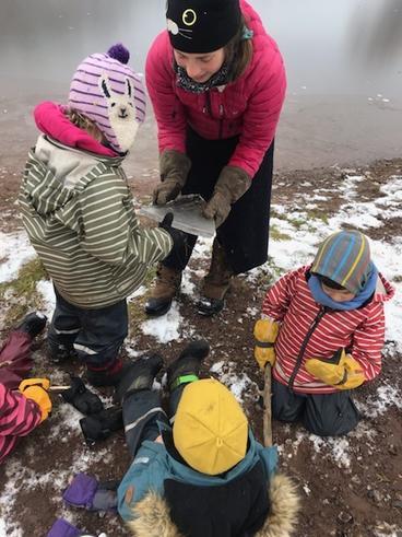 Three children and a teacher examining a shard of ice.