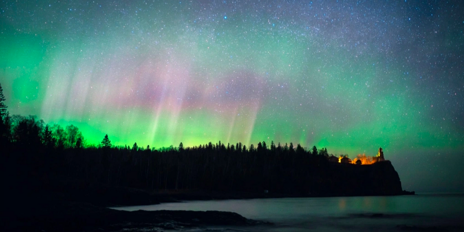 Northern lights backlight a peninsula with a lighthouse on Minnesota's north shore