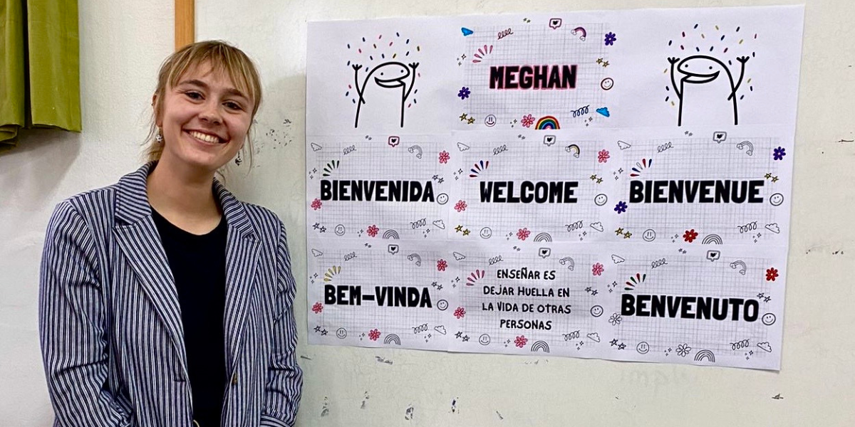 Meghan Hesterman smiling next to a welcome sign 
